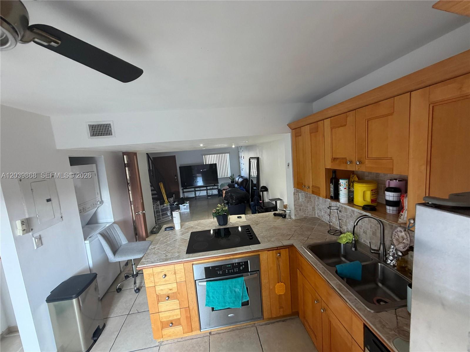 A kitchen with wood cabinets, tiled countertops, and a built-in oven overlooks a living area — 541 NW 82nd Ct # 375, Miami FL 33126, MIAMI, FL