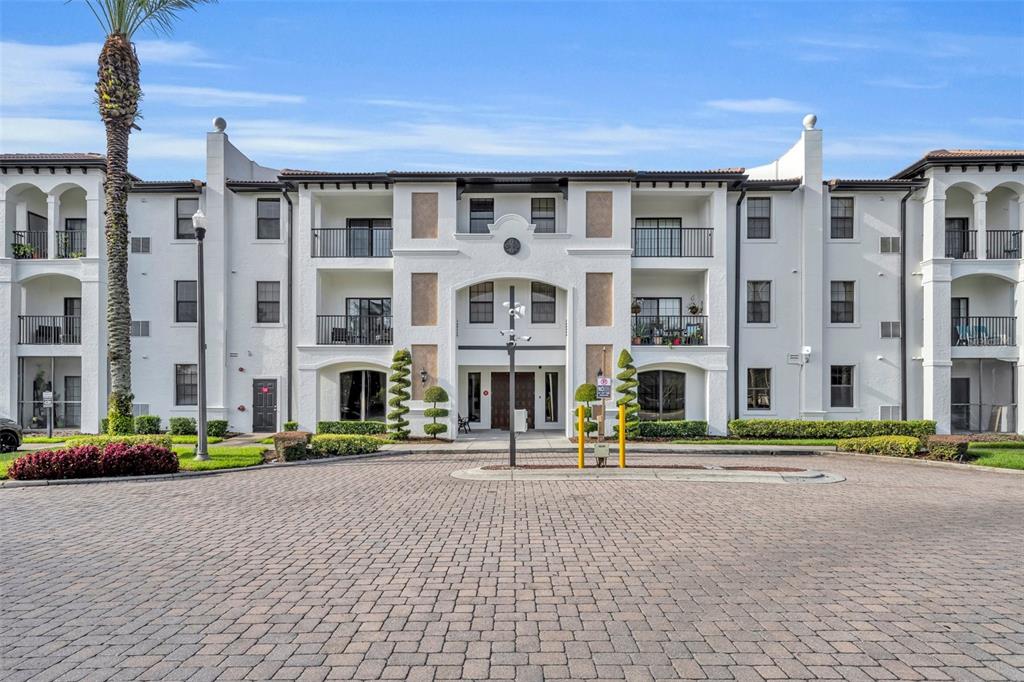 A multi-story white apartment building with balconies and a paved circular driveway in front — 5550 E MICHIGAN STREET UNIT 2232, ORLANDO, FL