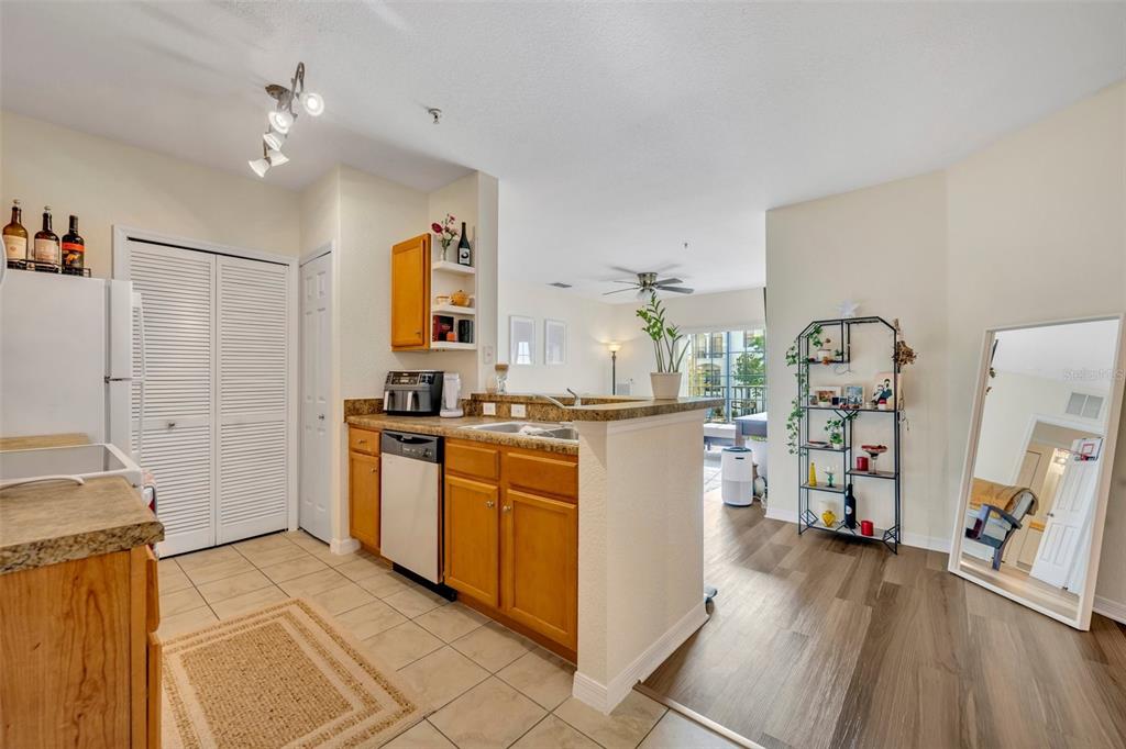 A kitchen with wood cabinets and tile floors opens to a living area with wood flooring — 5550 E MICHIGAN STREET UNIT 2232, ORLANDO, FL