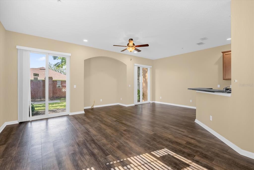 An open-concept living area features dark wood-look flooring, beige walls, and two sliding glass doors — 910 ASHWORTH OVERLOOK DRIVE UNIT A, APOPKA, FL