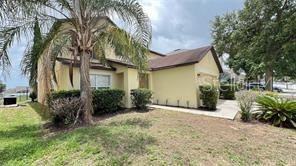 A two-story yellow house with a palm tree and a paved driveway in front — 216 VERDI STREET, DAVENPORT, FL
