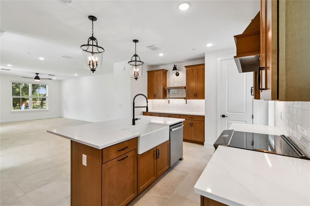 A kitchen features wood cabinets, white quartz countertops, a farmhouse sink, and pendant lighting — 194 PASQUALA, OVIEDO, FL