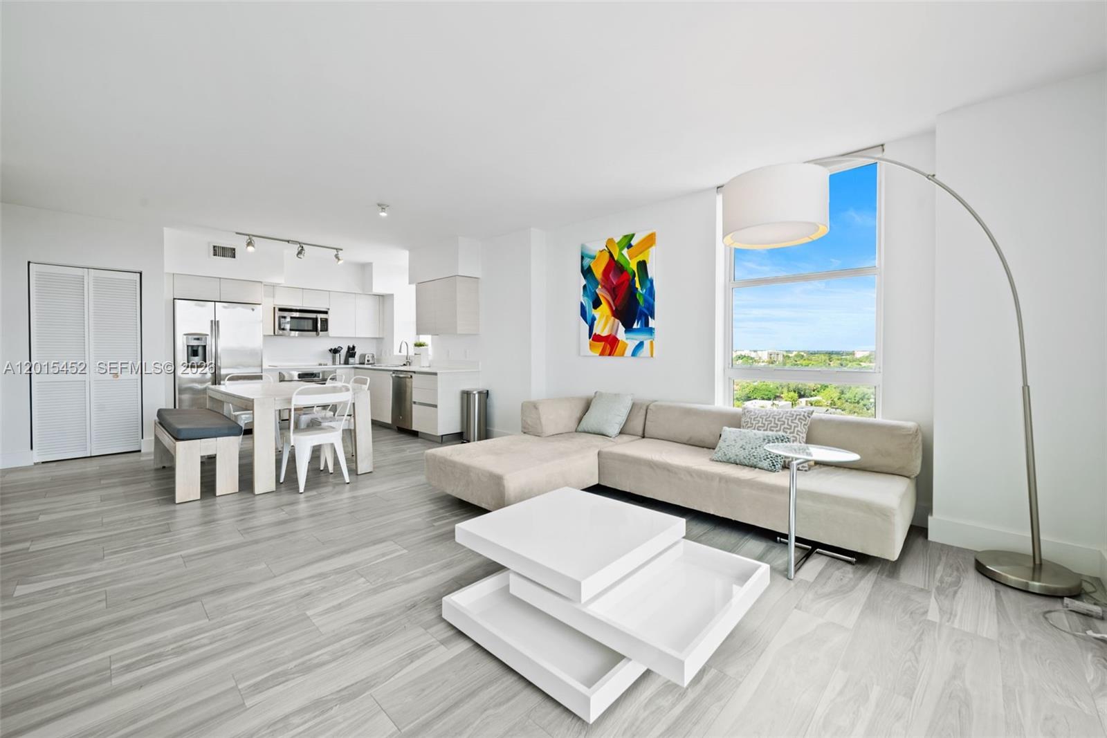 A modern open-concept living room and kitchen area features light wood flooring and large windows — 4250 Biscayne Blvd # 1009, Miami FL 33137, MIAMI, FL