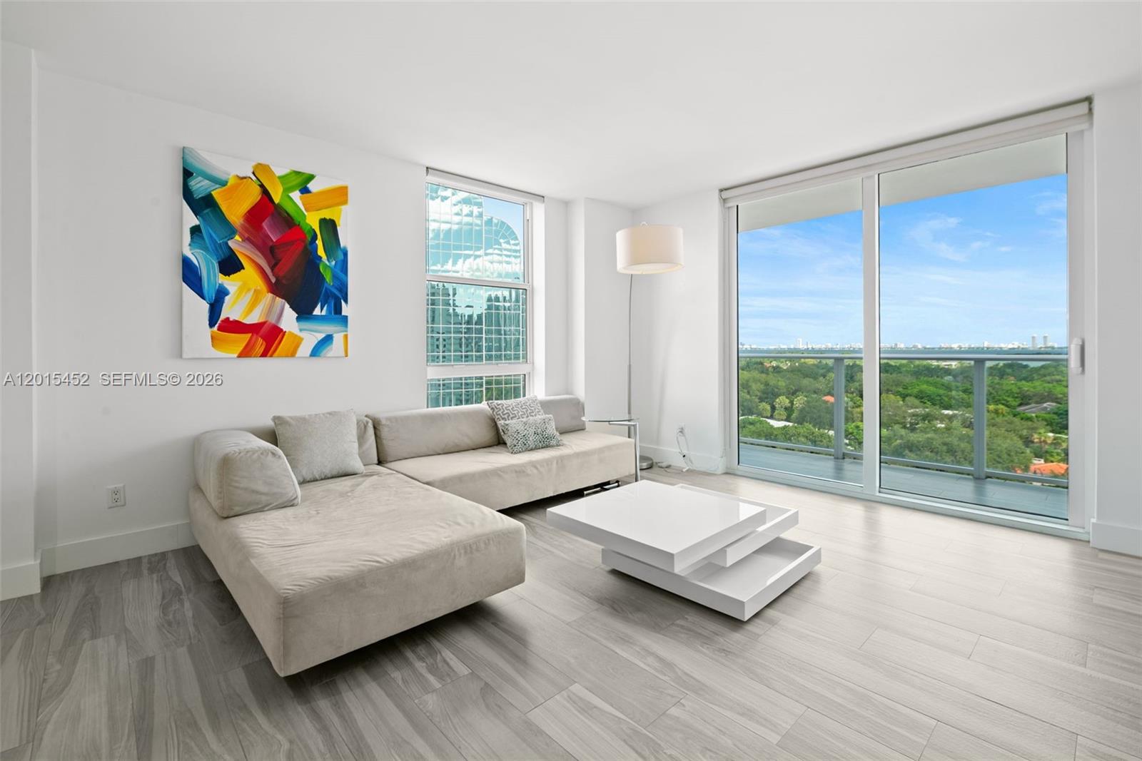 A modern living room features a beige sectional sofa, white coffee table, and floor-to-ceiling windows — 4250 Biscayne Blvd # 1009, Miami FL 33137, MIAMI, FL