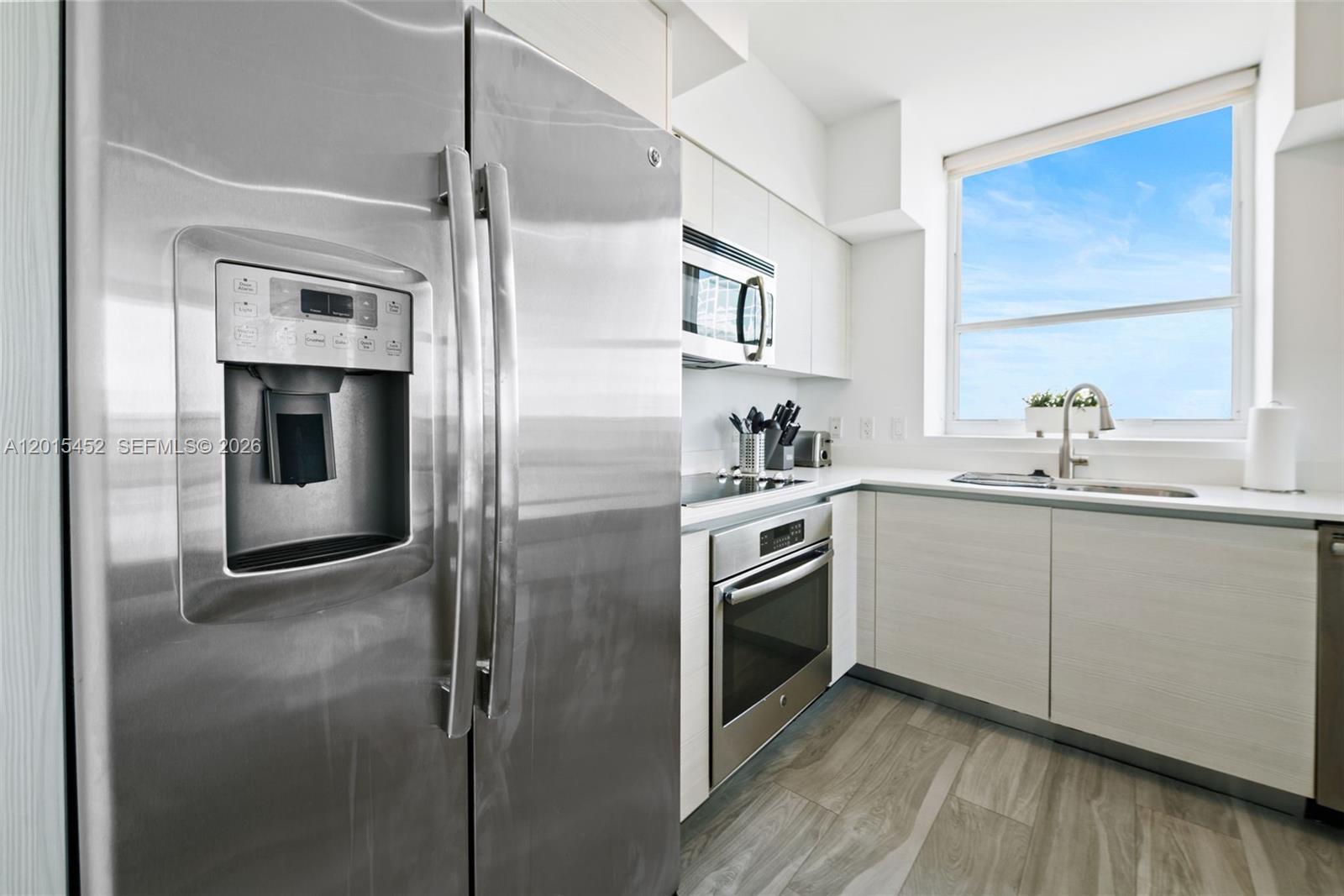 A modern kitchen features stainless steel appliances, light wood cabinetry, and a window with sky views — 4250 Biscayne Blvd # 1009, Miami FL 33137, MIAMI, FL