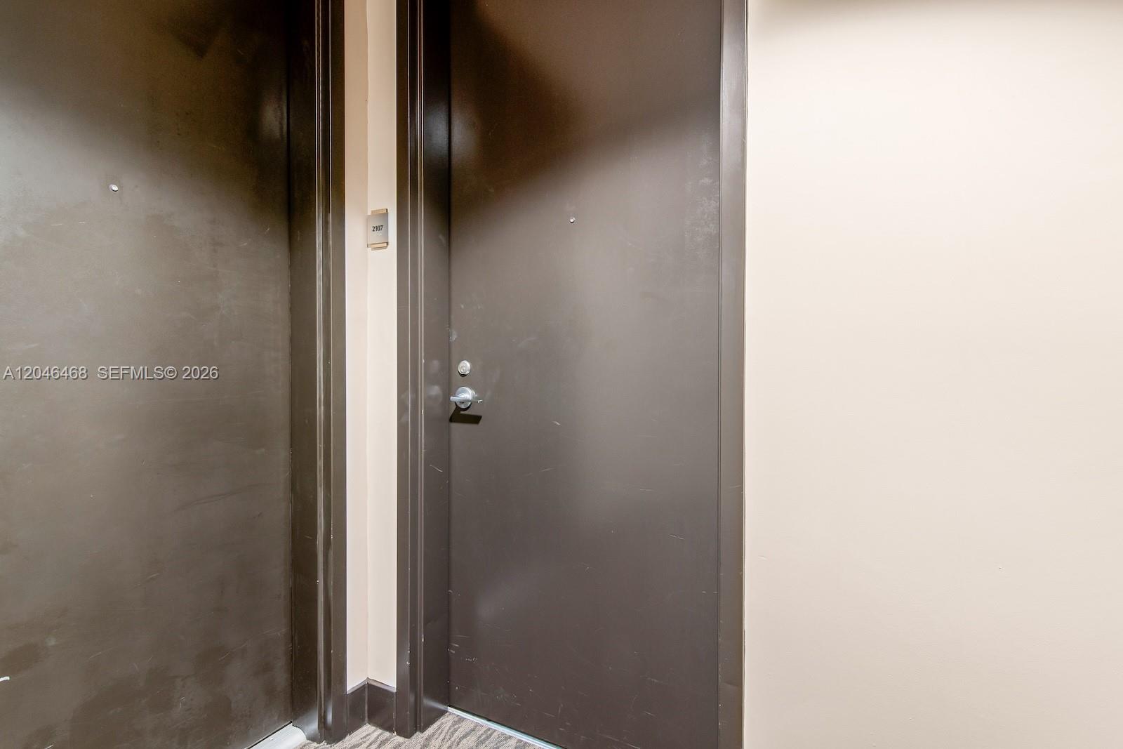 A dark brown door with a silver handle and a unit number sign — 79 SW 12th St, Miami FL 33130, MIAMI, FL