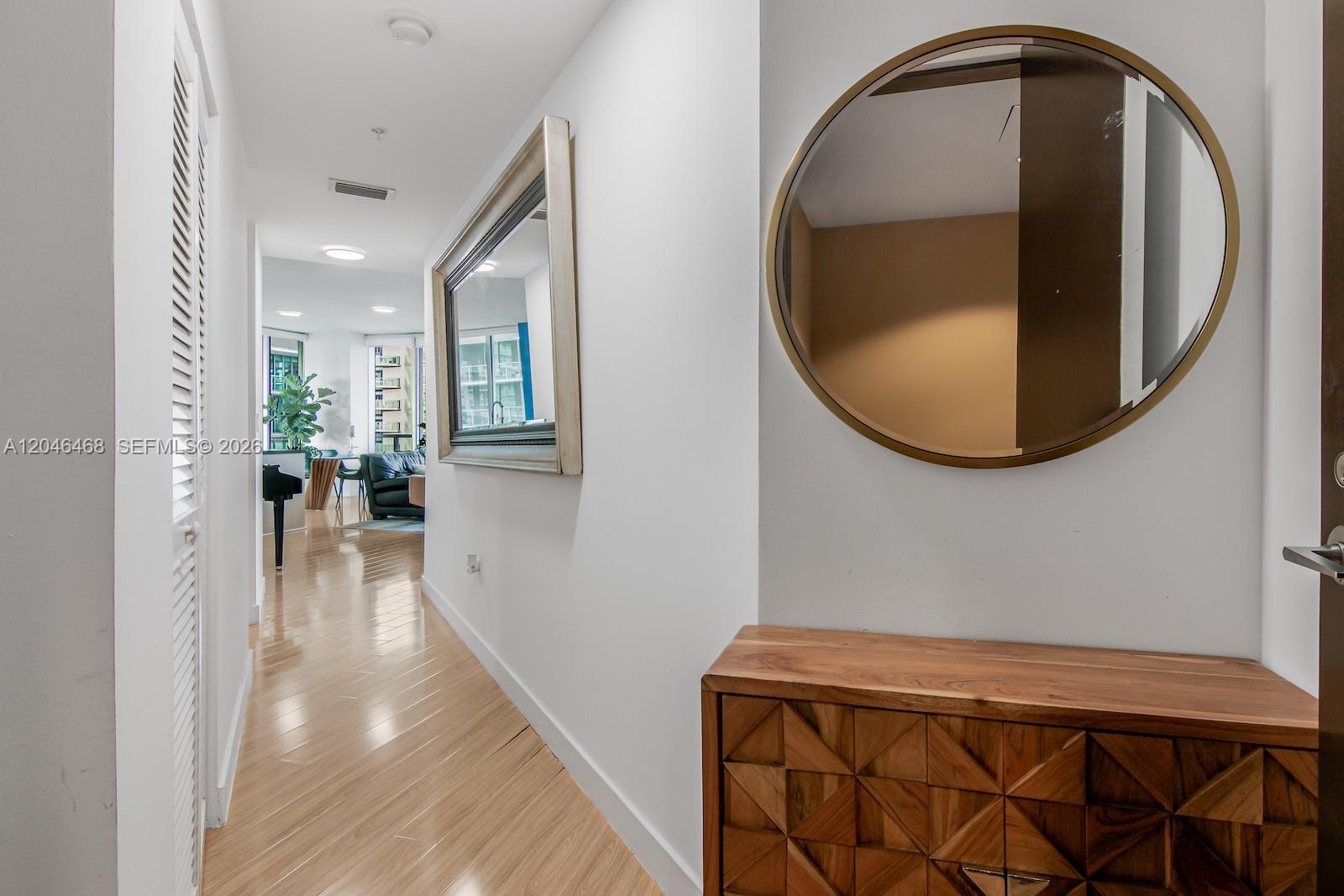 A hallway features light wood flooring, a wooden console table, and two wall mirrors — 79 SW 12th St, Miami FL 33130, MIAMI, FL