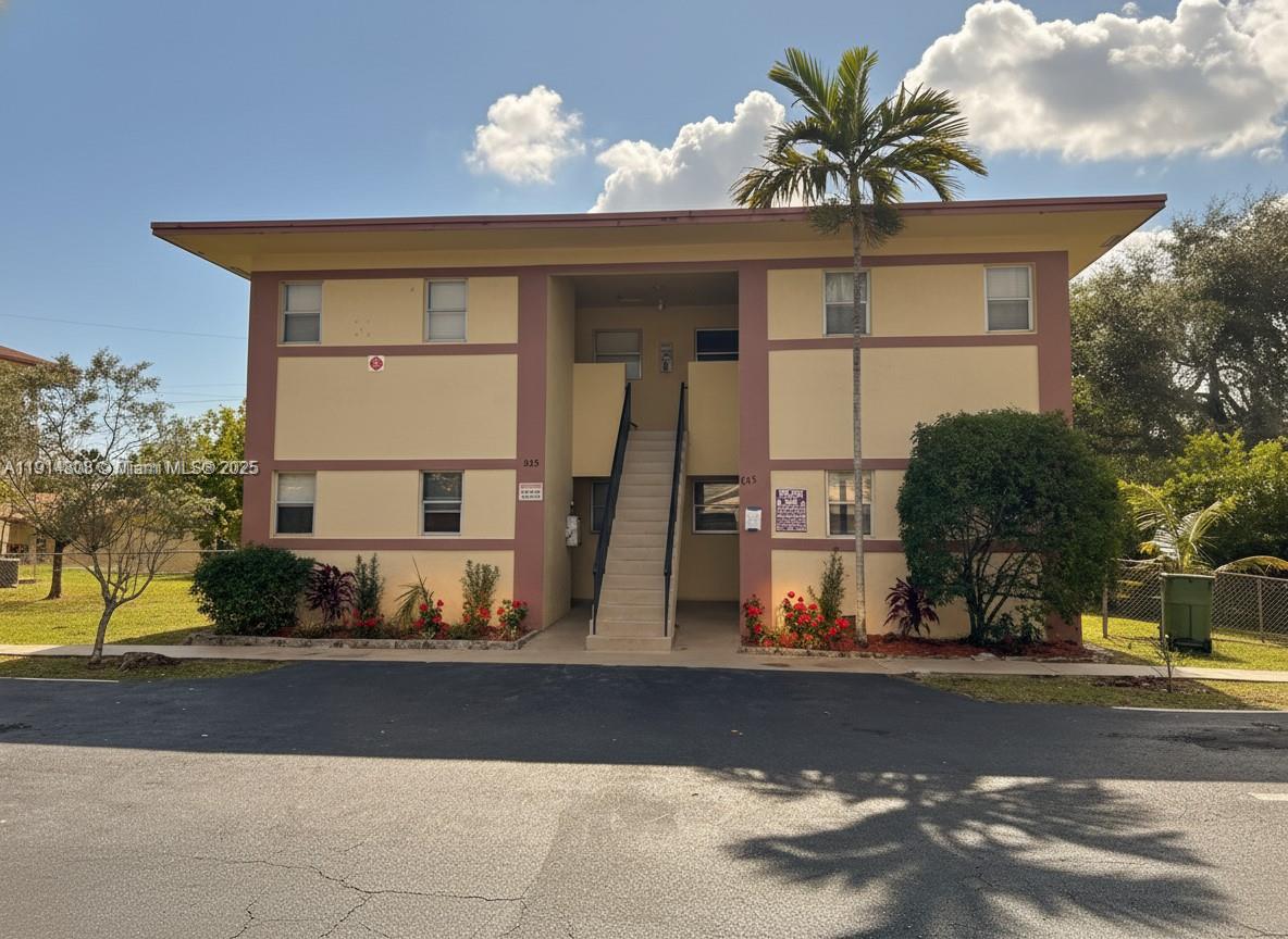 A two-story apartment building with a central staircase and tan stucco exterior walls — 825 SW 10th St, Hallandale Beach FL 33009, HALLANDALE BEACH, FL
