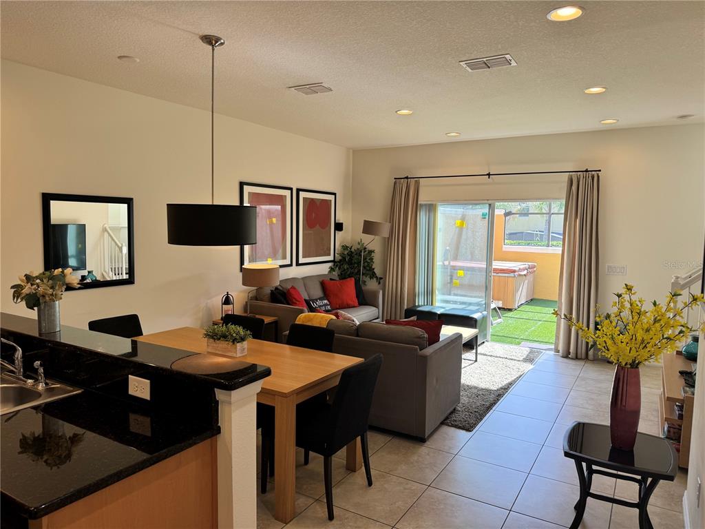 A dining area and living room with tile floors, a sliding glass door, and patio — 3003 WHITE ORCHID ROAD, KISSIMMEE, FL