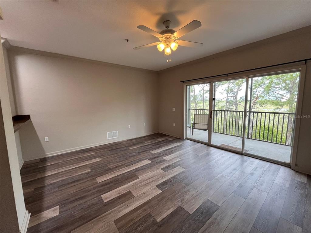 An empty room with wood-look flooring, a ceiling fan, and sliding glass doors to a balcony — 14200 AVALON ROAD UNIT 431, WINTER GARDEN, FL