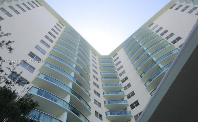 A low-angle view of a tall, white residential building with curved balconies and glass railings — 3801 S Ocean Dr # 8U, Hollywood FL 33019, HOLLYWOOD, FL