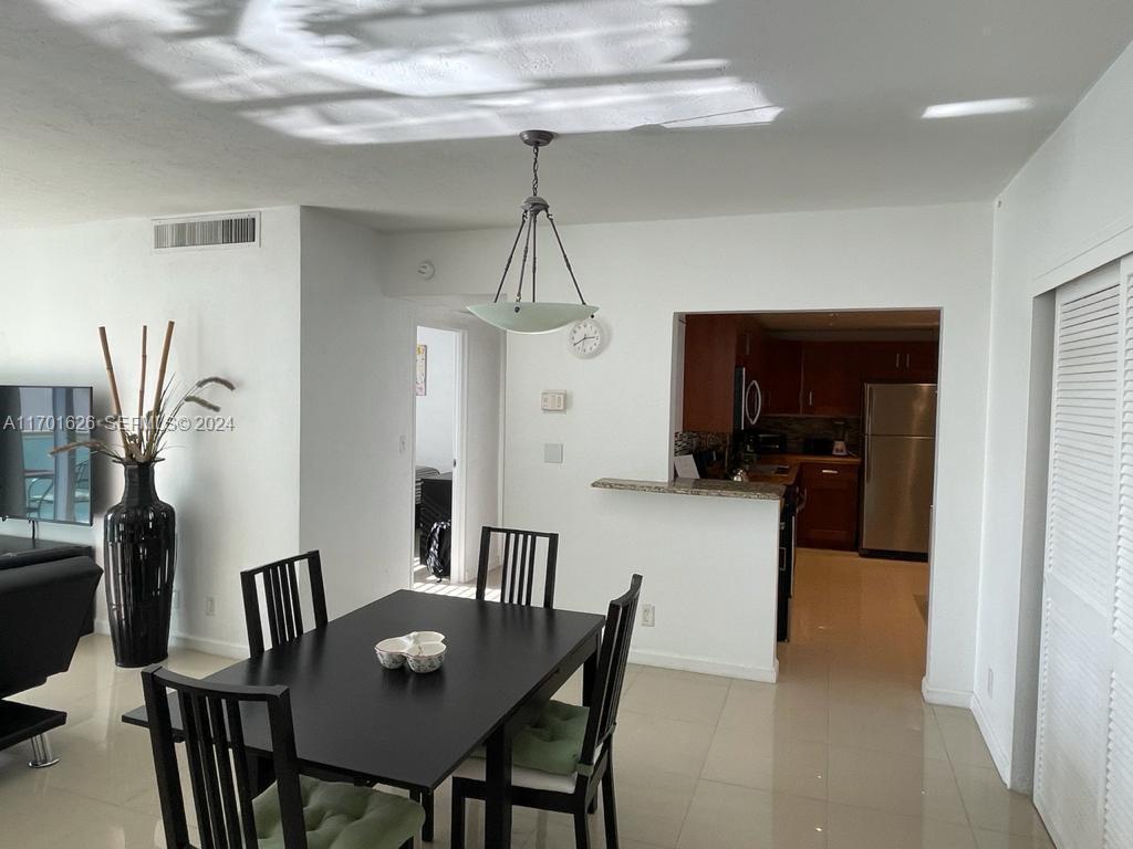 A dining area with a black table and chairs sits adjacent to an open kitchen — 3801 S Ocean Dr # 8U, Hollywood FL 33019, HOLLYWOOD, FL