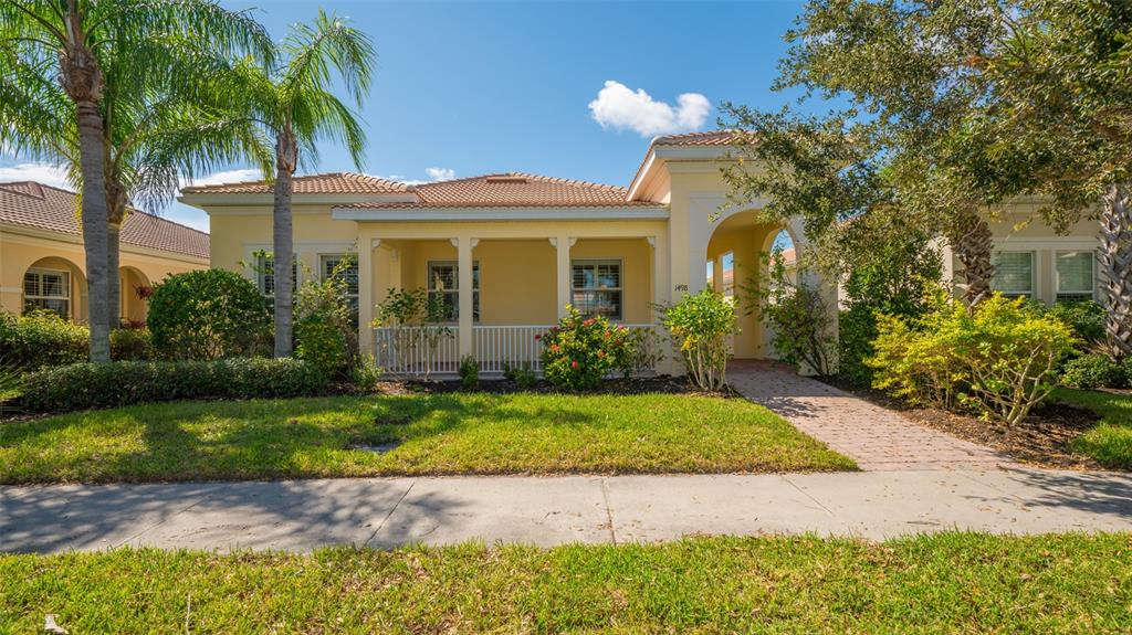 A yellow single-story house with a covered front porch, arched entryway, and a tiled roof — 1498 ERNESTO DRIVE, SARASOTA, FL
