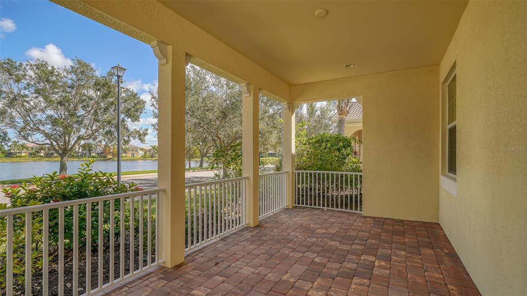 A covered patio with brick pavers, white railings, and a view of a lake — 1498 ERNESTO DRIVE, SARASOTA, FL