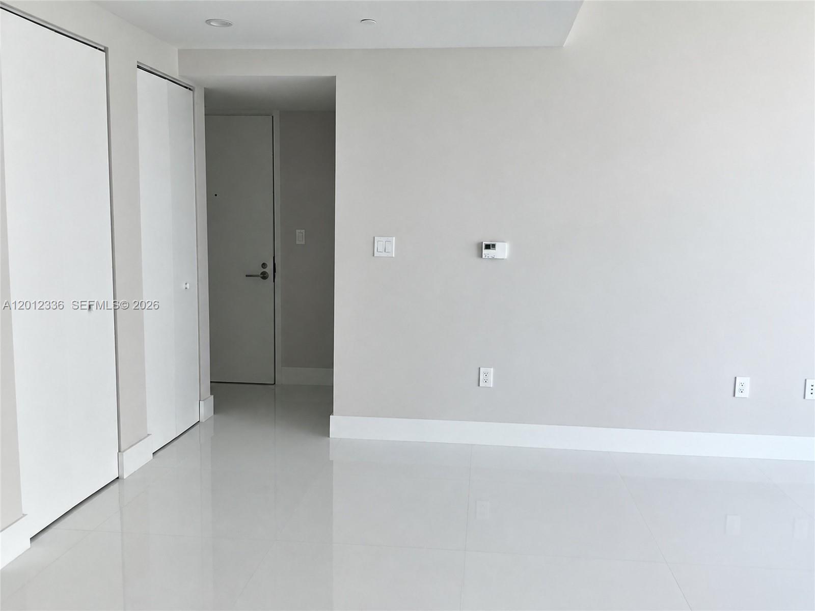 A modern kitchen features wood-grain cabinets, stainless steel appliances, and white tile flooring — 1300 S Miami Ave # 4507, Miami FL 33130, MIAMI, FL
