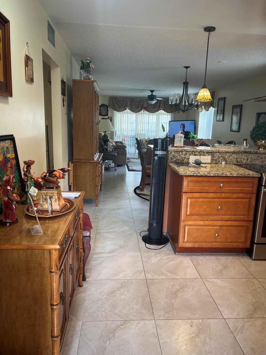 A view from a kitchen looking into a living room with tile floors and cabinetry — 25 Lake Vista Trail # 106, FL 34952, FL