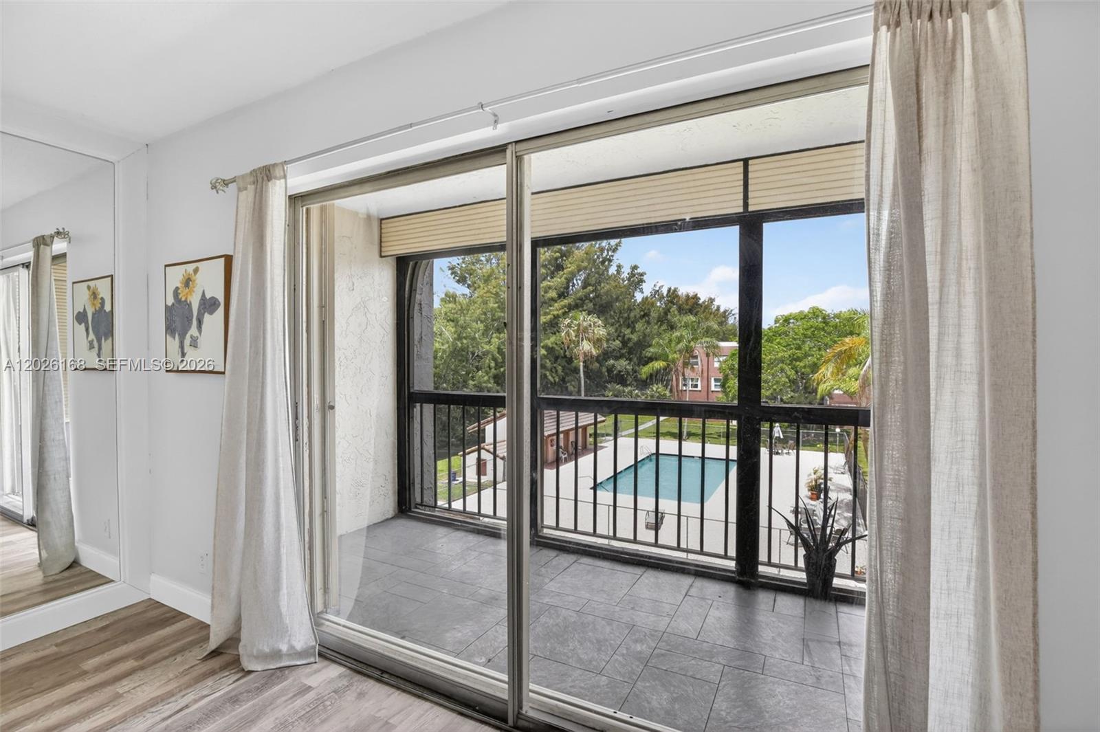 A room with sliding glass doors opens onto a balcony overlooking a swimming pool — 7020 Nova Dr # 308D, Davie FL 33317, DAVIE, FL