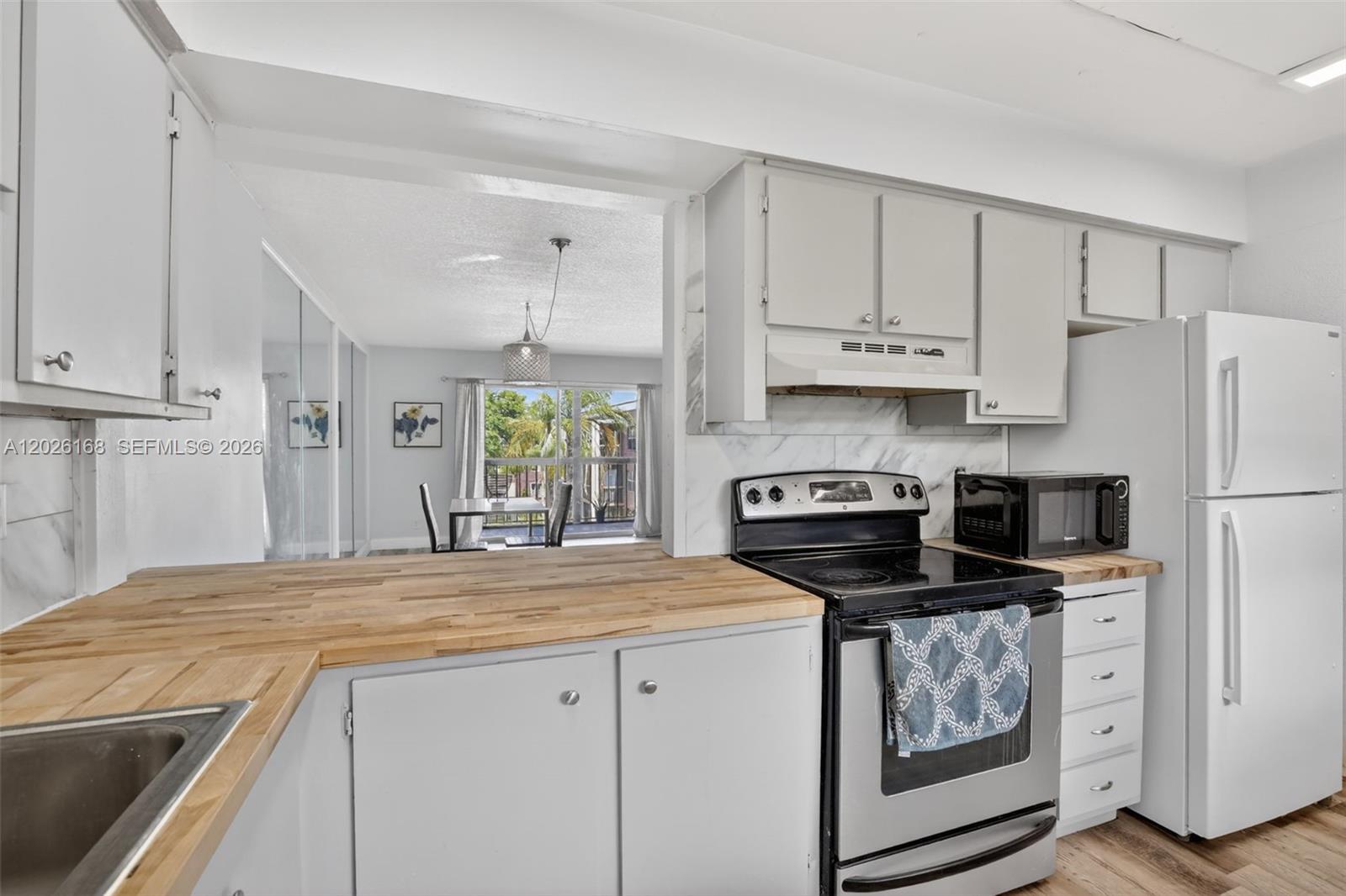A kitchen features light gray cabinets, a wood countertop, and stainless steel appliances — 7020 Nova Dr # 308D, Davie FL 33317, DAVIE, FL
