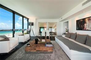 A modern living room features a large sectional sofa, wooden coffee table, and floor-to-ceiling windows — 101 20th St # 1907, Miami Beach FL 33139, MIAMI BEACH, FL