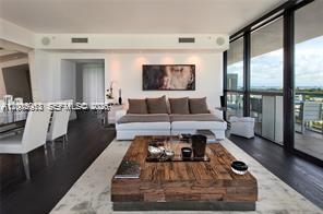 A modern living room features a large wooden coffee table, white sofa, and floor-to-ceiling windows — 101 20th St # 1907, Miami Beach FL 33139, MIAMI BEACH, FL