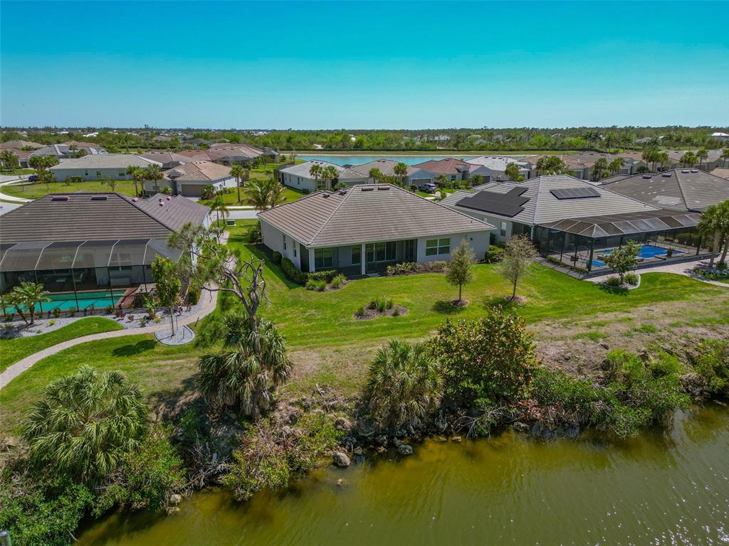 An aerial view of a suburban neighborhood featuring houses with pools near a lake — 14500 PONCE DE LEON TRAIL, PORT CHARLOTTE, FL
