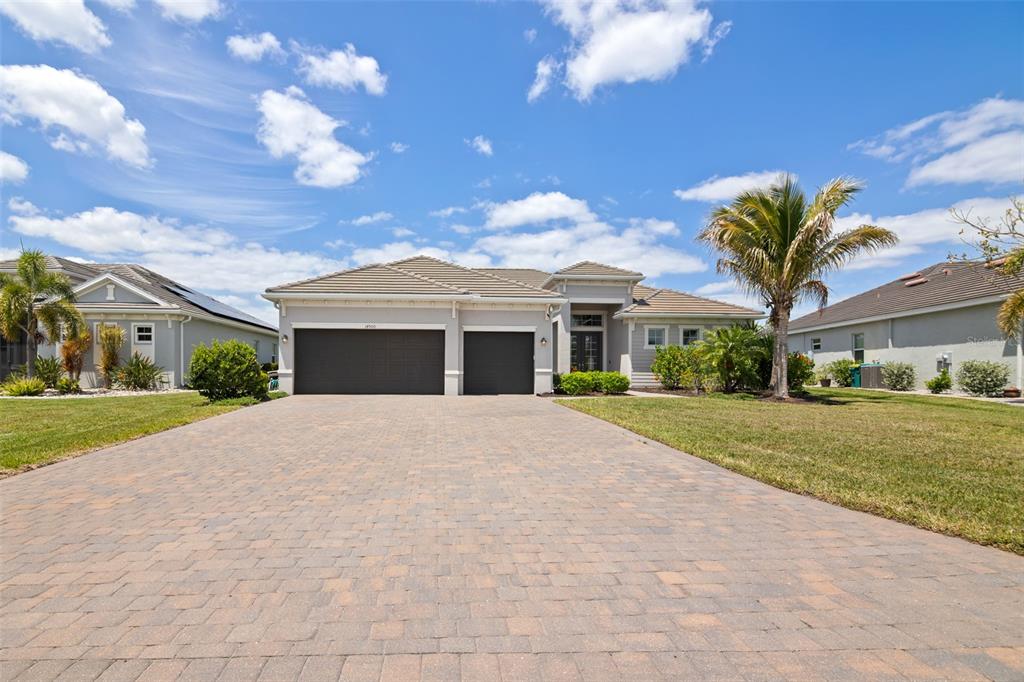 A single-story house with a paved driveway, a three-car garage, and a palm tree — 14500 PONCE DE LEON TRAIL, PORT CHARLOTTE, FL
