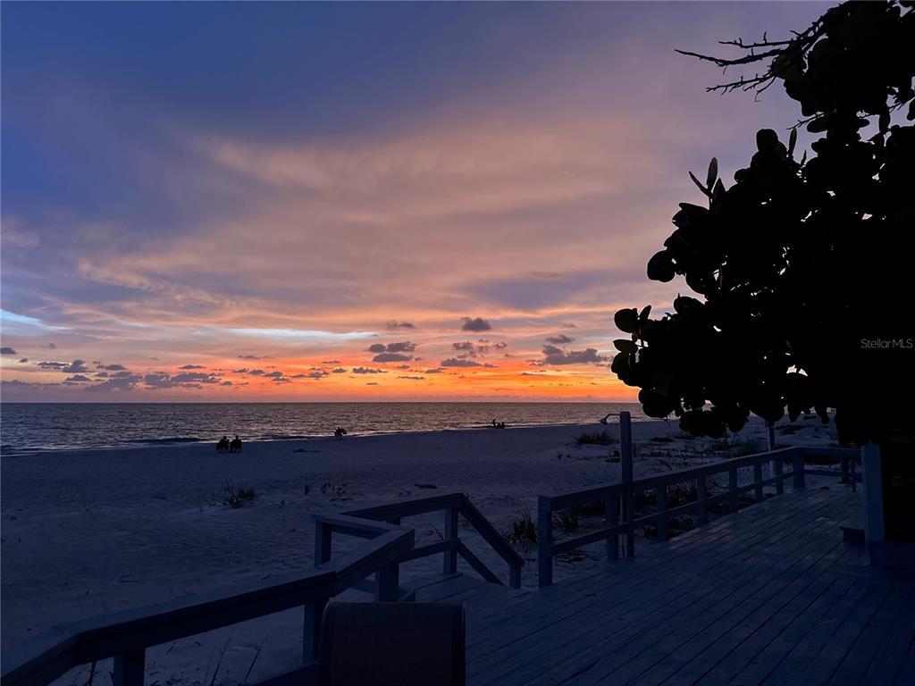 A wooden deck overlooks a sandy beach and ocean during a vibrant sunset — 2823 GULF OF MEXICO DRIVE, LONGBOAT KEY, FL