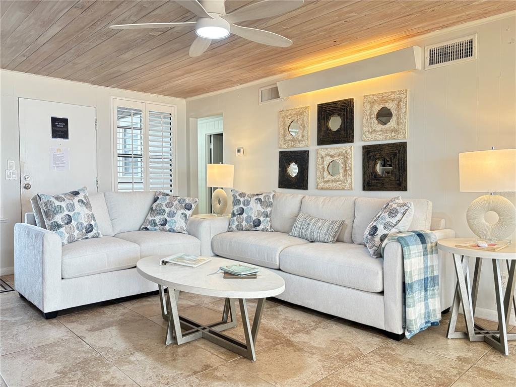 A living room features a white sectional sofa, a coffee table, and wall-mounted mirror decor — 2823 GULF OF MEXICO DRIVE, LONGBOAT KEY, FL
