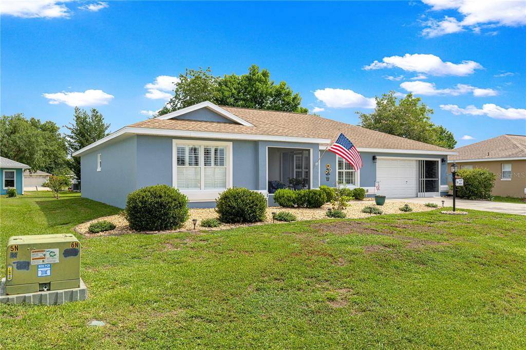 A single-story blue house with a front porch, American flag, and a green lawn — 6091 SW 84TH PLACE ROAD, OCALA, FL