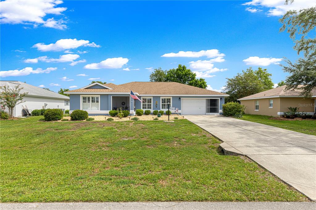 A single-story blue house with a two-car garage and a front lawn — 6091 SW 84TH PLACE ROAD, OCALA, FL