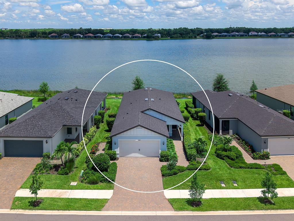 An aerial view of a single-story house with a white garage facing a lake — 6524 SILVERSTAR DRIVE, SARASOTA, FL