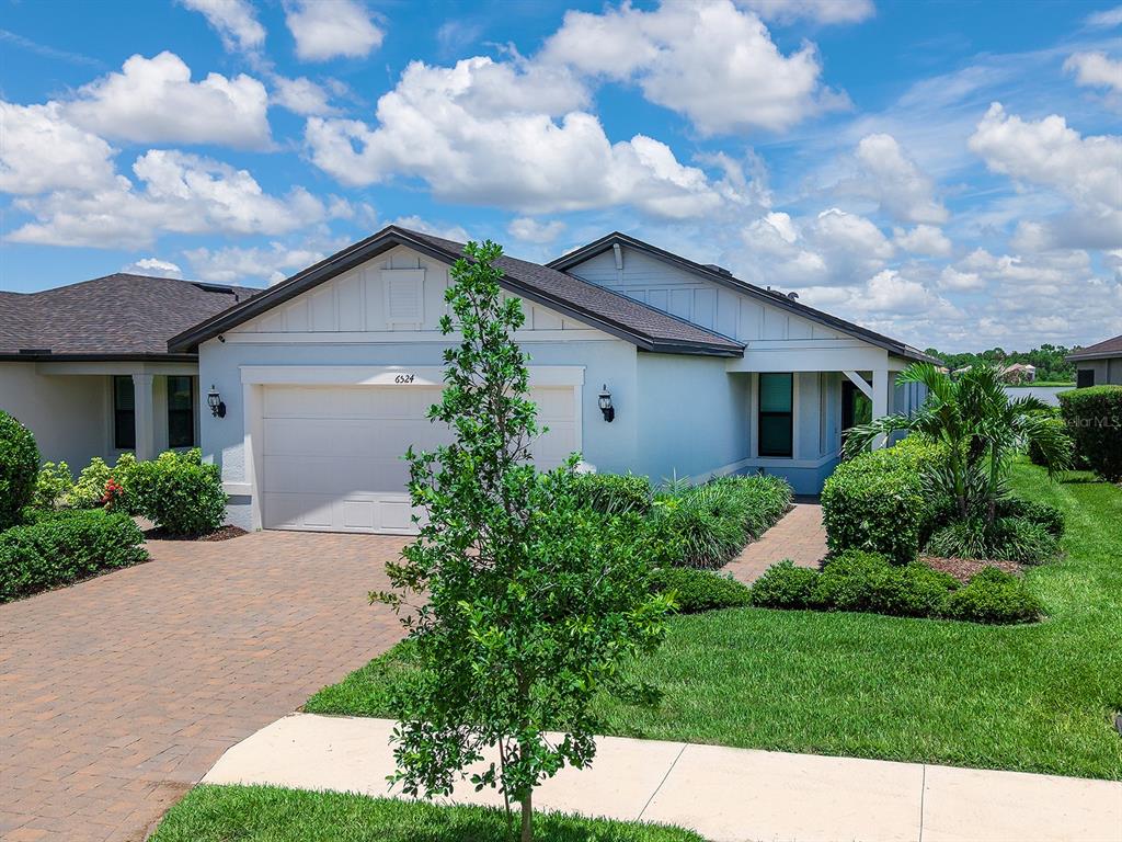 A single-story house with a white exterior, a two-car garage, and a brick paver driveway — 6524 SILVERSTAR DRIVE, SARASOTA, FL