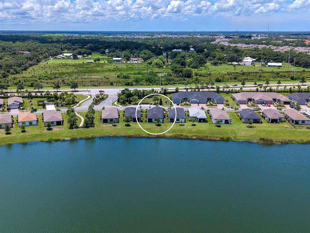 An aerial view shows a residential house with a dark roof situated by a lake — 6524 SILVERSTAR DRIVE, SARASOTA, FL