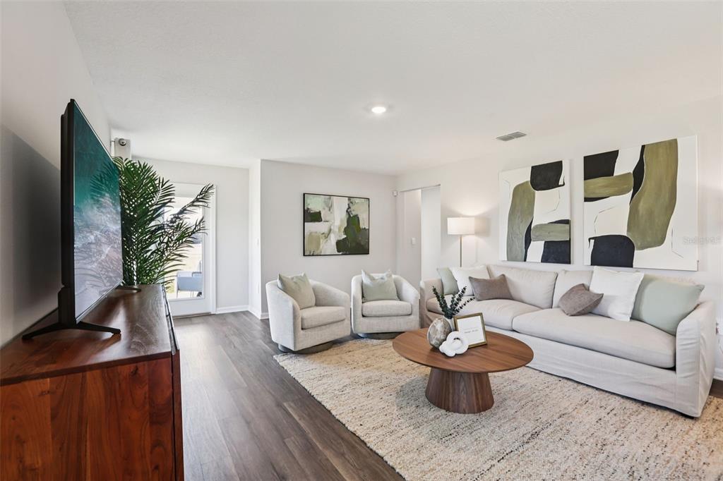 A living room features a sofa, two armchairs, a wooden coffee table, and wall art — 7953 FORREST FOX WAY, LAKELAND, FL