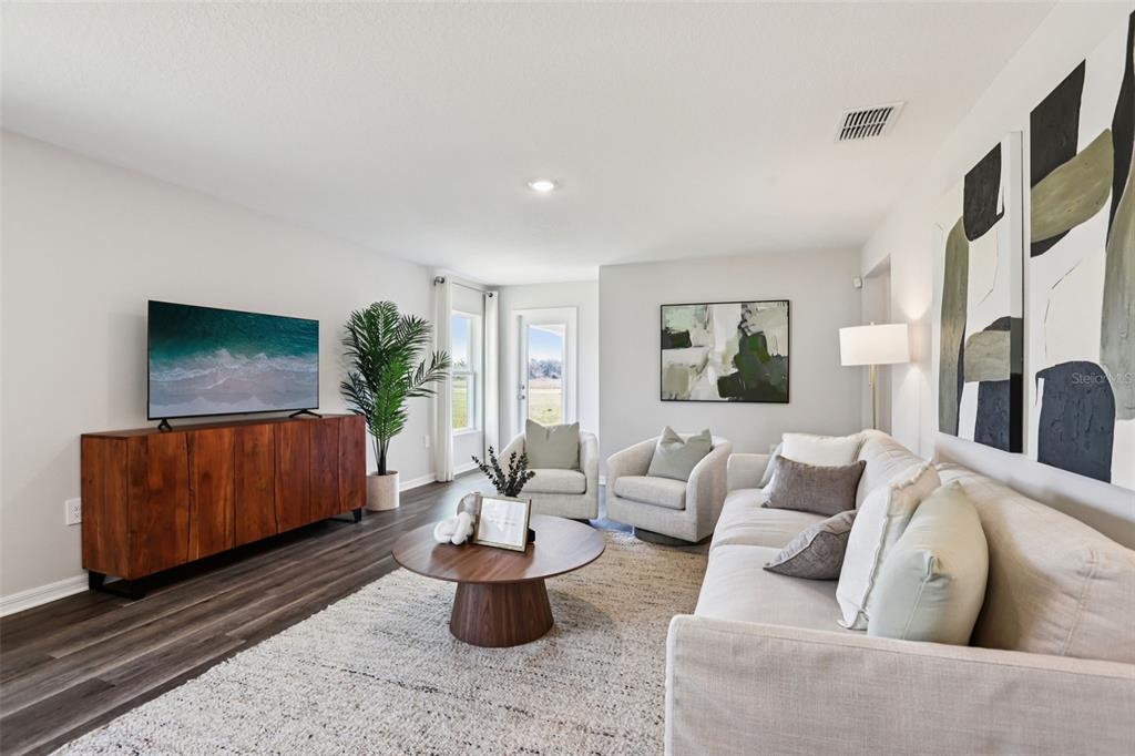 A living room features a wooden media console, a sofa, two armchairs, and a coffee table — 7953 FORREST FOX WAY, LAKELAND, FL