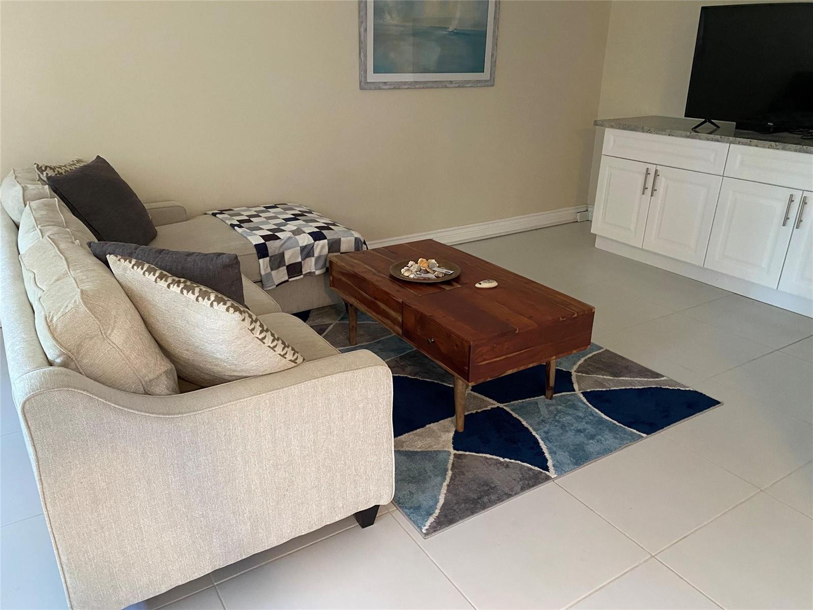 A living room features a beige sectional sofa, a wooden coffee table, and a geometric rug — 209 Ventnor M # 209, Deerfield Beach FL 33442, DEERFIELD BEACH, FL