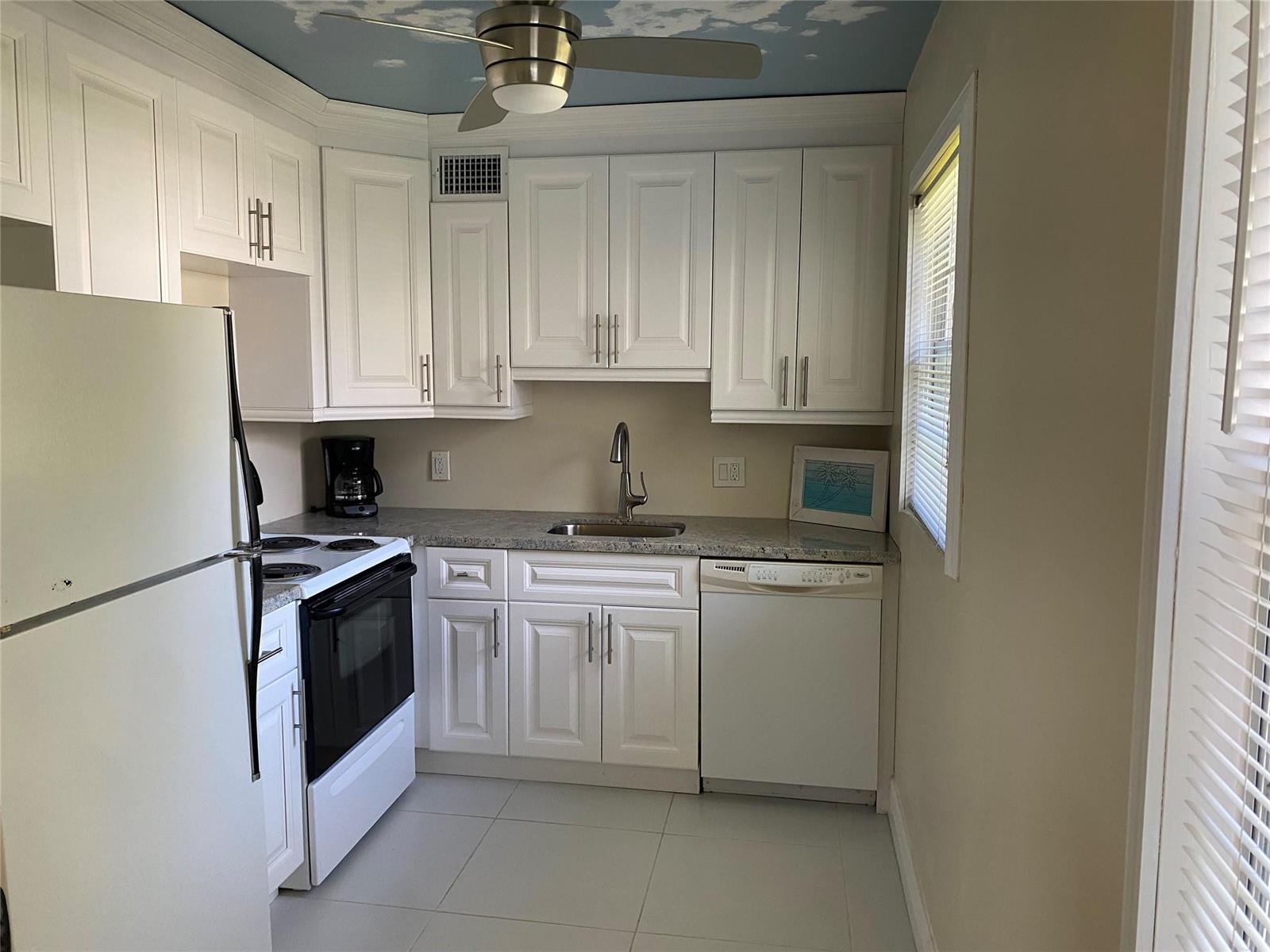 A dining area features a round glass table with four black chairs on tile flooring — 209 Ventnor M # 209, Deerfield Beach FL 33442, DEERFIELD BEACH, FL