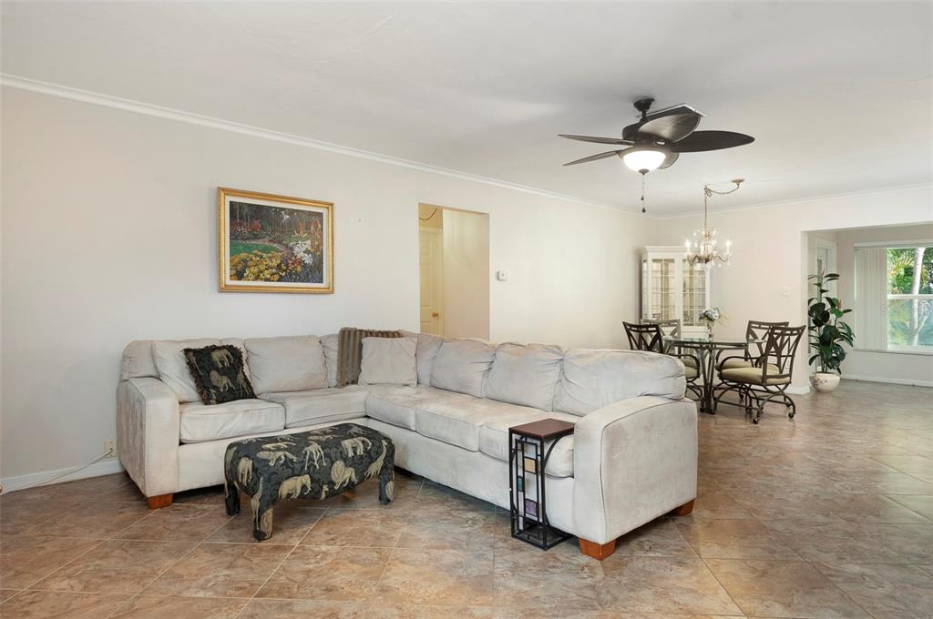 A living room with a large sectional sofa, tile flooring, and an adjacent dining area — 8303 ANNWOOD ROAD, SEMINOLE, FL