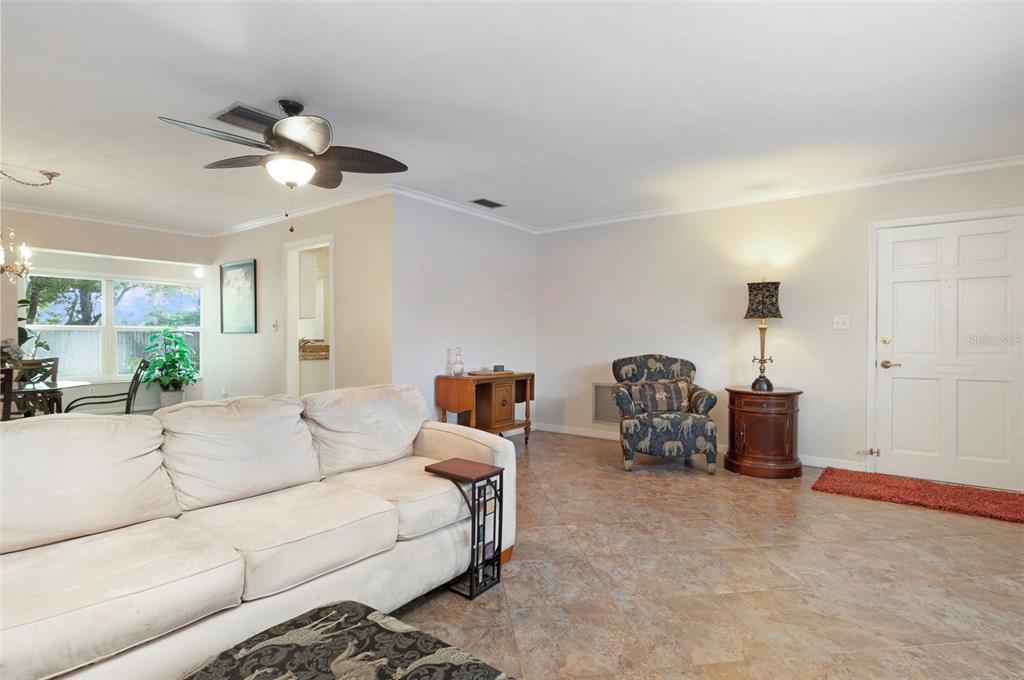 A living room features a white sofa, tiled floors, a ceiling fan, and an entryway door — 8303 ANNWOOD ROAD, SEMINOLE, FL