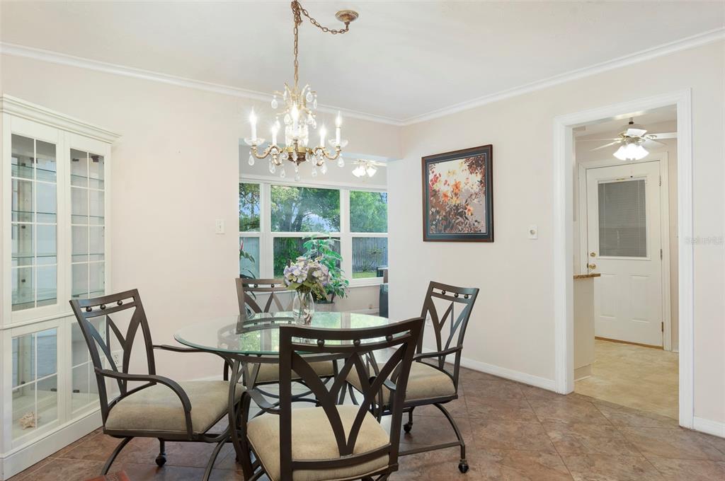 A dining room with a glass table, four chairs, a chandelier, and a white cabinet — 8303 ANNWOOD ROAD, SEMINOLE, FL