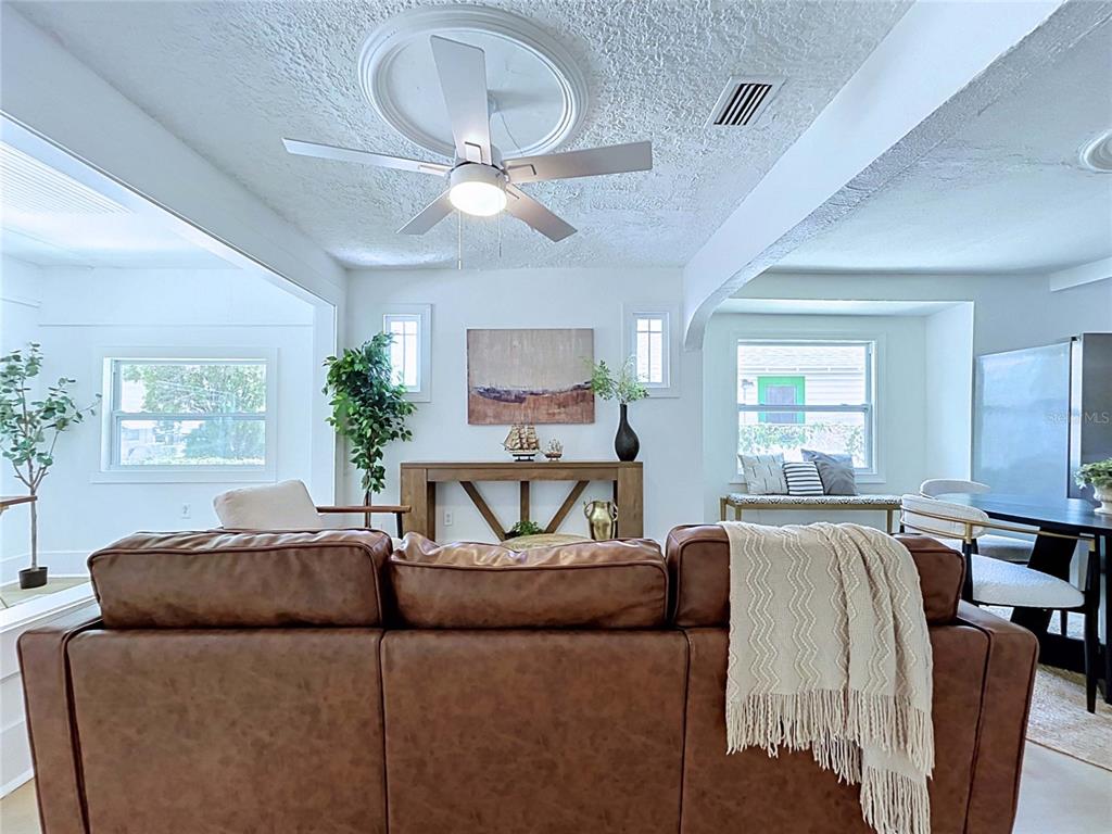 A living room features a brown leather sofa, a ceiling fan, and a wooden console table — 1835 24TH STREET S, ST PETERSBURG, FL