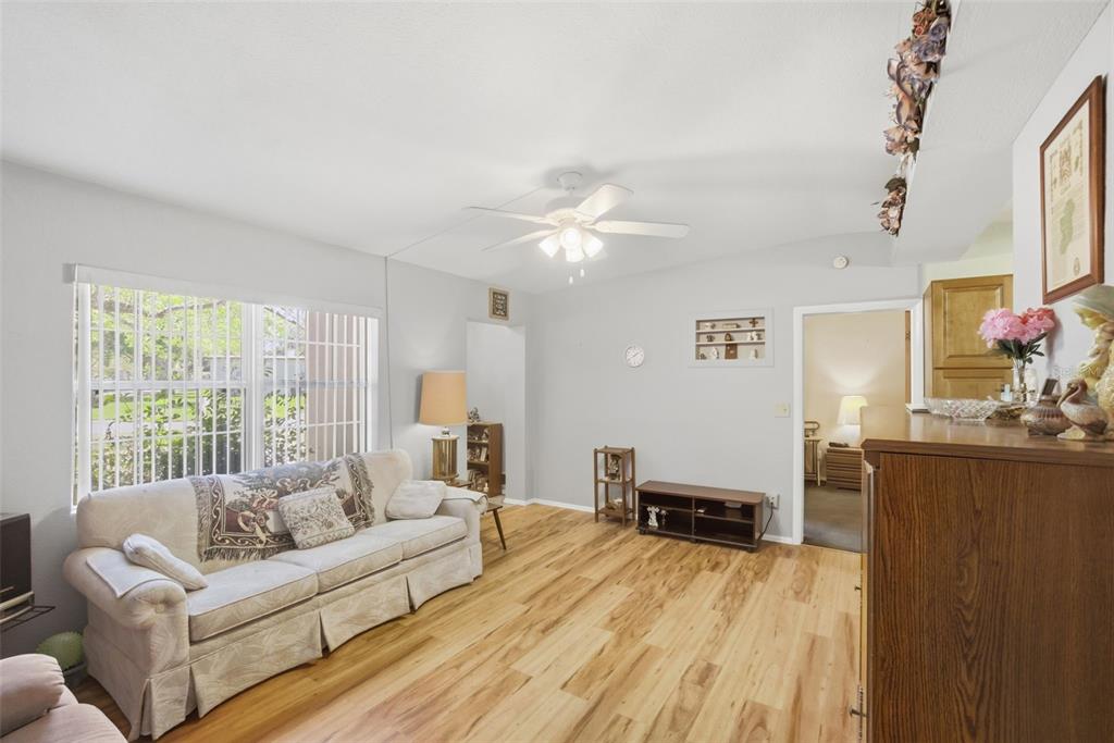 A living room features light wood flooring, a beige sofa, and a ceiling fan — 481 KENTIA ROAD, CASSELBERRY, FL