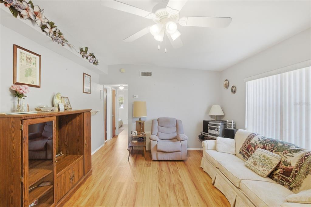A living room features light wood flooring, a ceiling fan, a sofa, and a recliner — 481 KENTIA ROAD, CASSELBERRY, FL