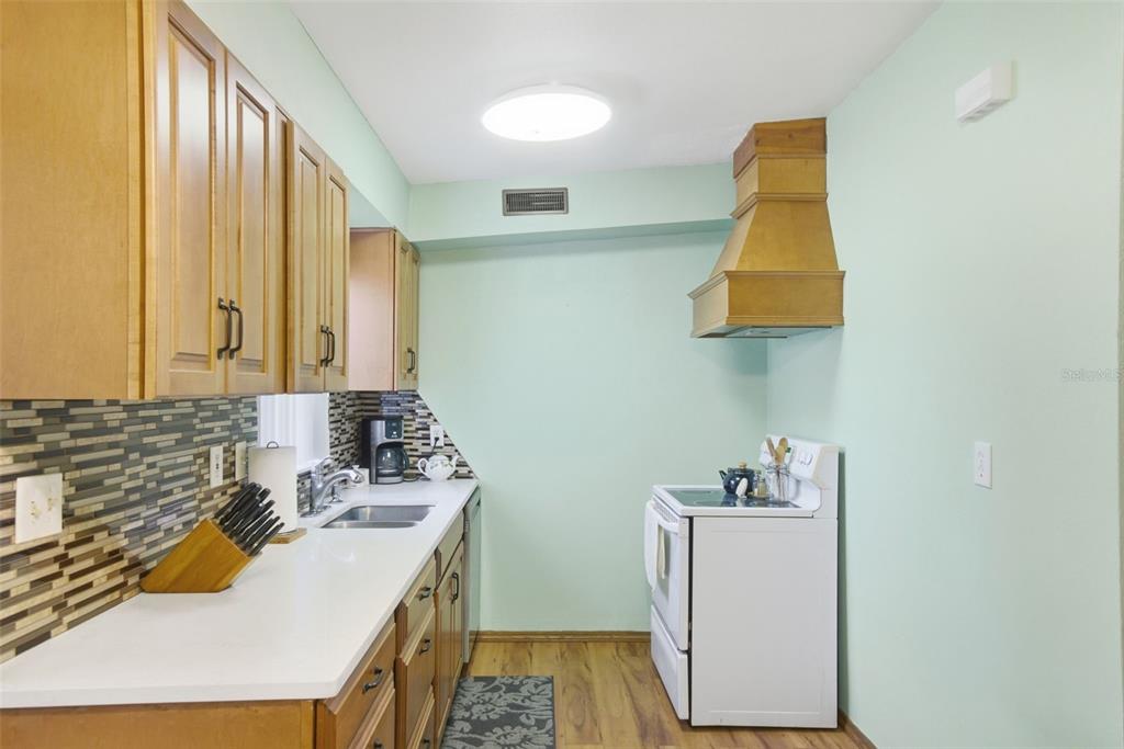 A kitchen with light green walls, wood cabinets, white countertops, and a white stove — 481 KENTIA ROAD, CASSELBERRY, FL