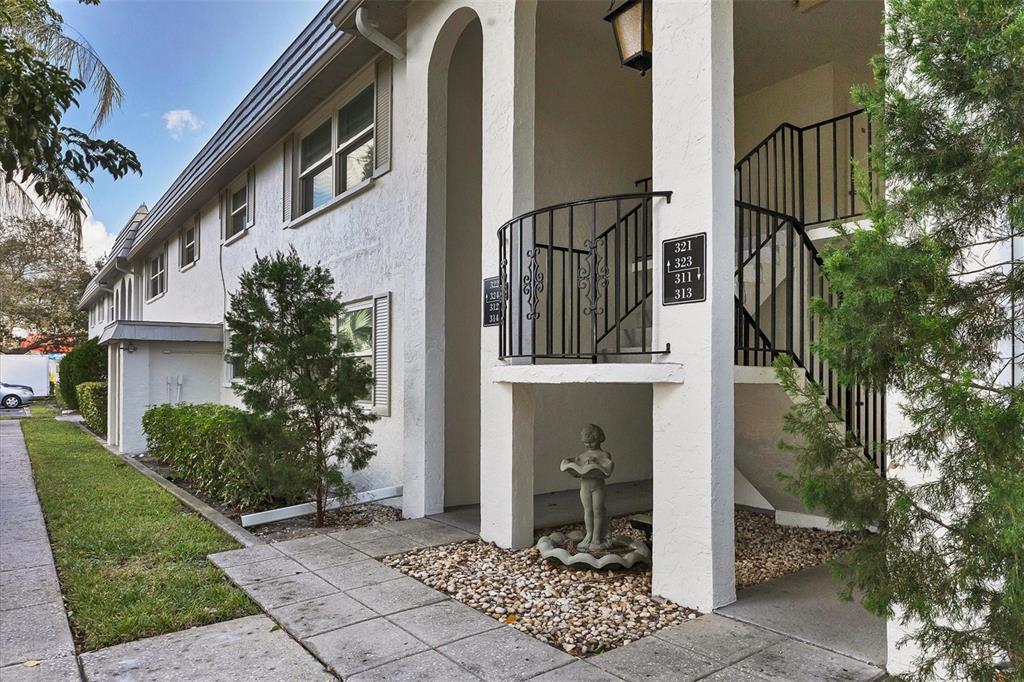 The exterior of a multi-story apartment building features a white stucco facade and staircases — 5800 HOLLYWOOD BOULEVARD UNIT 312, SARASOTA, FL
