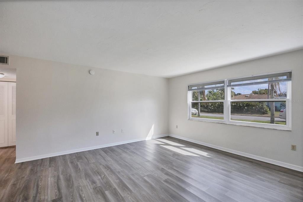 An empty room with light gray walls, wood-look flooring, and a large window — 5800 HOLLYWOOD BOULEVARD UNIT 312, SARASOTA, FL