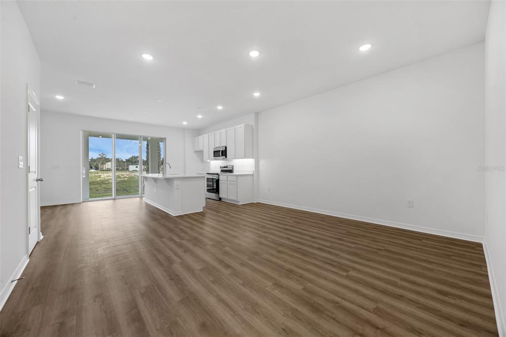 An open-concept kitchen and living area features white cabinetry, an island, and wood-look flooring — 1160 CYPRESS ELM DRIVE, DELAND, FL