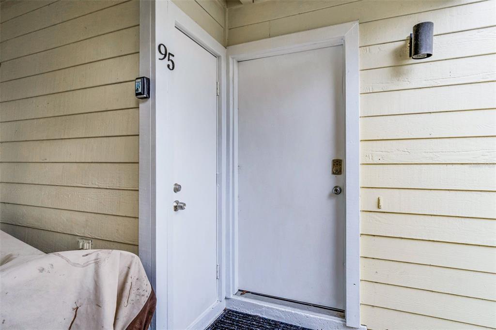 A white door marked with the number 95 sits next to another white door on a beige-sided exterior — 5017 LAGUNA BAY CIRCLE UNIT 95, KISSIMMEE, FL