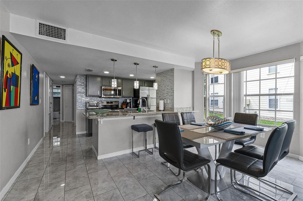 A kitchen with grey cabinets and a dining area with a table and chairs — 5017 LAGUNA BAY CIRCLE UNIT 95, KISSIMMEE, FL