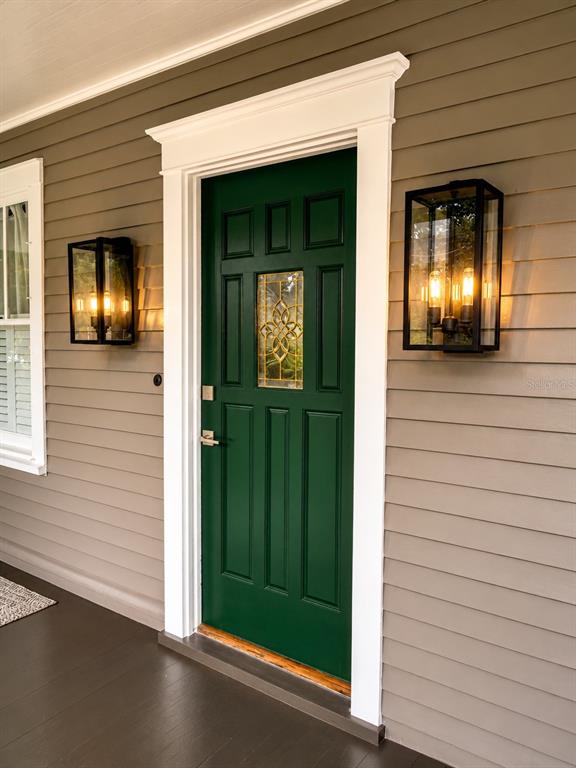 A dark green front door with a decorative glass insert is flanked by two wall sconces — 605 S ORLEANS AVENUE, TAMPA, FL